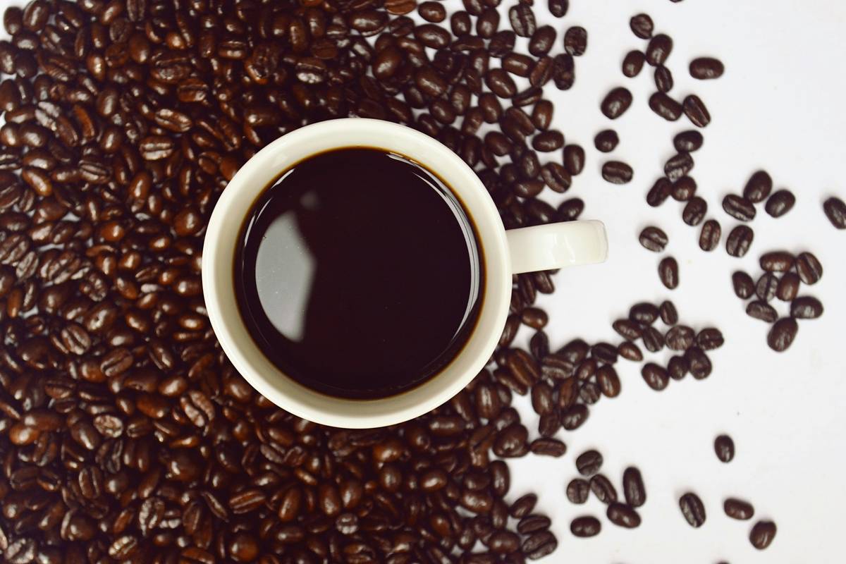 Close-up of organic coffee beans next to a skincare serum bottle, illustrating the link between what you drink and your skin health – should coffee be organic