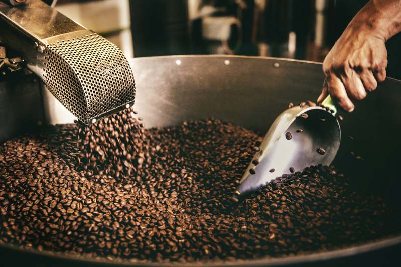 Founder grinding organic coffee beans for handmade skincare in sunlit studio